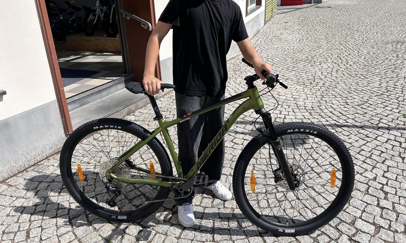 Ein Junge schiebt sein neues Mountainbike aus dem Laden
